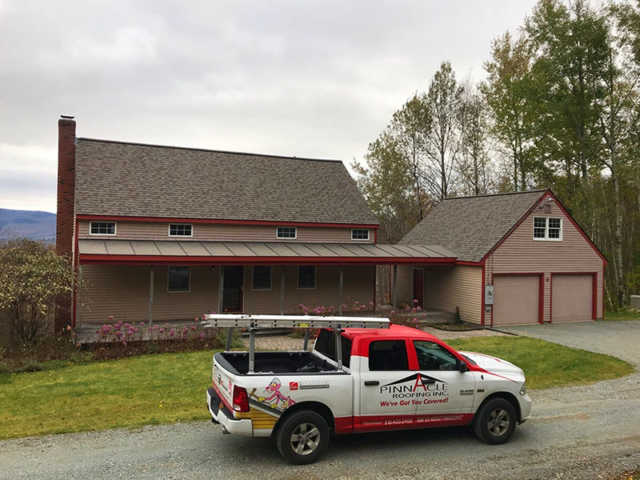 Home with brown siding, dark brown roof, red trim, pinnacle roofing truck in front of home