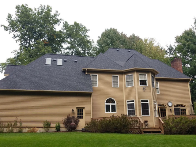 replacement roof with black shingles on a tan house with white trim