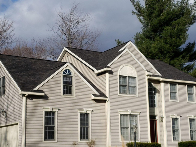 black shingle replacement roof on a light tan sided home