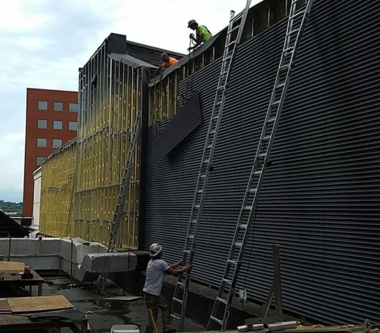 Workers wearing hardhats installing commercial siding